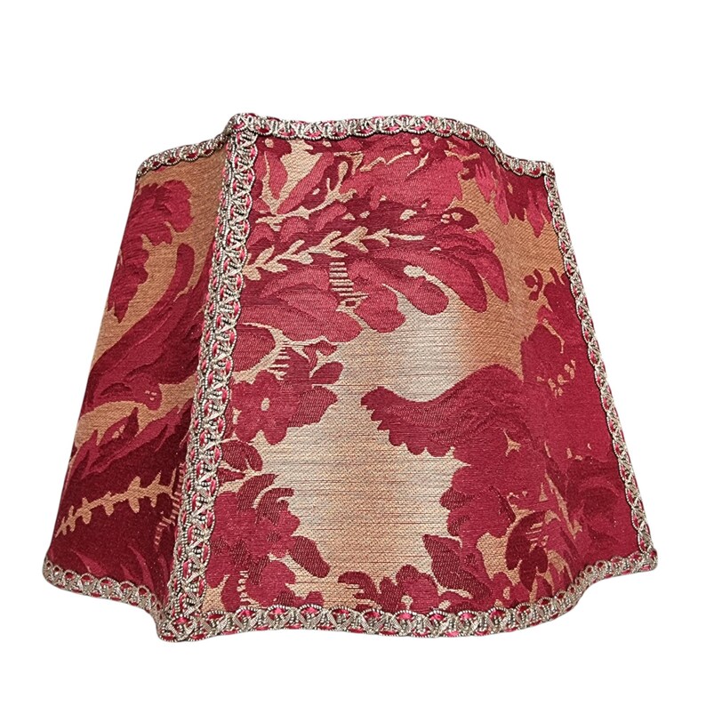 Puede incluir: Una pantalla de l&aacute;mpara roja y dorada con un patr&oacute;n floral y un ribete plateado.