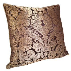 May include: A decorative throw pillow with a gold and brown damask pattern. The pillow is made of a soft, luxurious fabric and has a subtle sheen.