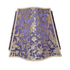May include: A purple lampshade with a gold trim and a floral pattern.