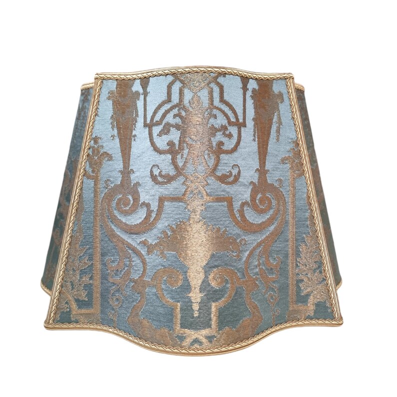 May include: A blue and gold lampshade with a decorative pattern. The lampshade is made of fabric and has a scalloped edge.