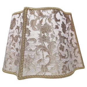 May include: A beige lampshade with a gold trim and a floral pattern.