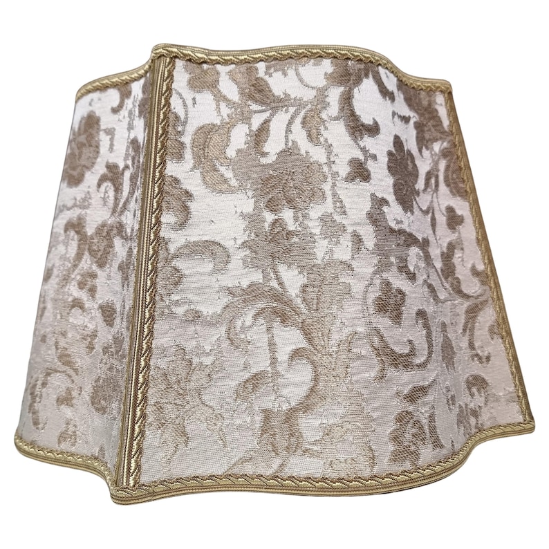 May include: A beige lampshade with a gold trim and a floral pattern.