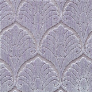 May include: A close-up of a soft, textured fabric with a repeating pattern of stylized, overlapping fan shapes. The fabric is a light purple color.