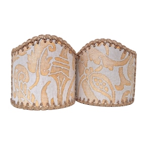 Könnte beinhalten: Zwei weiße Lampenschirme mit einem goldenen Paisley-Muster und goldenen Besatz.