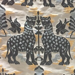 Pode incluir: Um tecido estampado em preto e branco com um desenho repetido de dois leopardos estilizados que se olham. Os leopardos est&atilde;o em p&eacute; sobre suas patas traseiras e t&ecirc;m as caudas enroladas ao redor de seus corpos. O tecido tem um fundo claro com uma textura sutil.