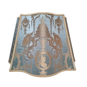 May include: A blue lampshade with a gold trim and a decorative pattern of a vase with birds and foliage.