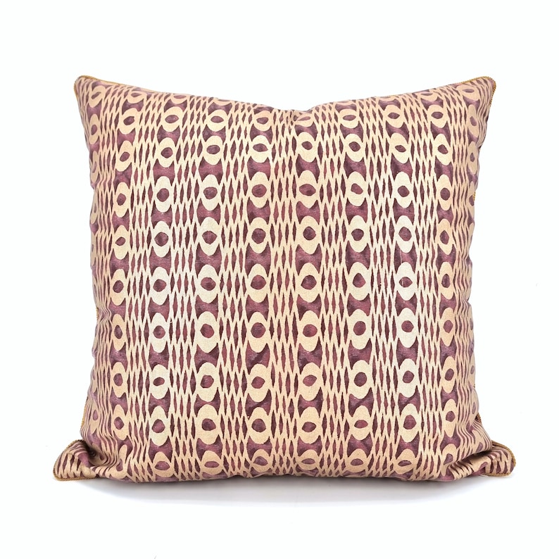 Op de afbeelding: Een decoratief kussen met een geometrisch patroon in beige en bordeaux tinten.