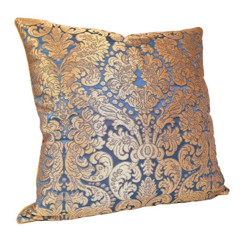 May include: A blue and gold decorative throw pillow with a damask pattern.