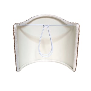 May include: A white lampshade with a brown trim. The shade is curved and has a metal wire loop for hanging.