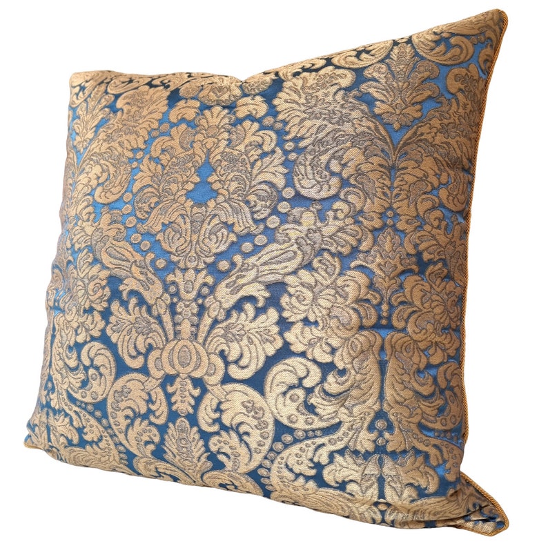 May include: A blue and gold decorative throw pillow with a damask pattern.