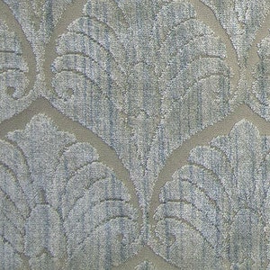 May include: A close-up of a textured fabric with a light gray background and a blue and white pattern of stylized leaves.