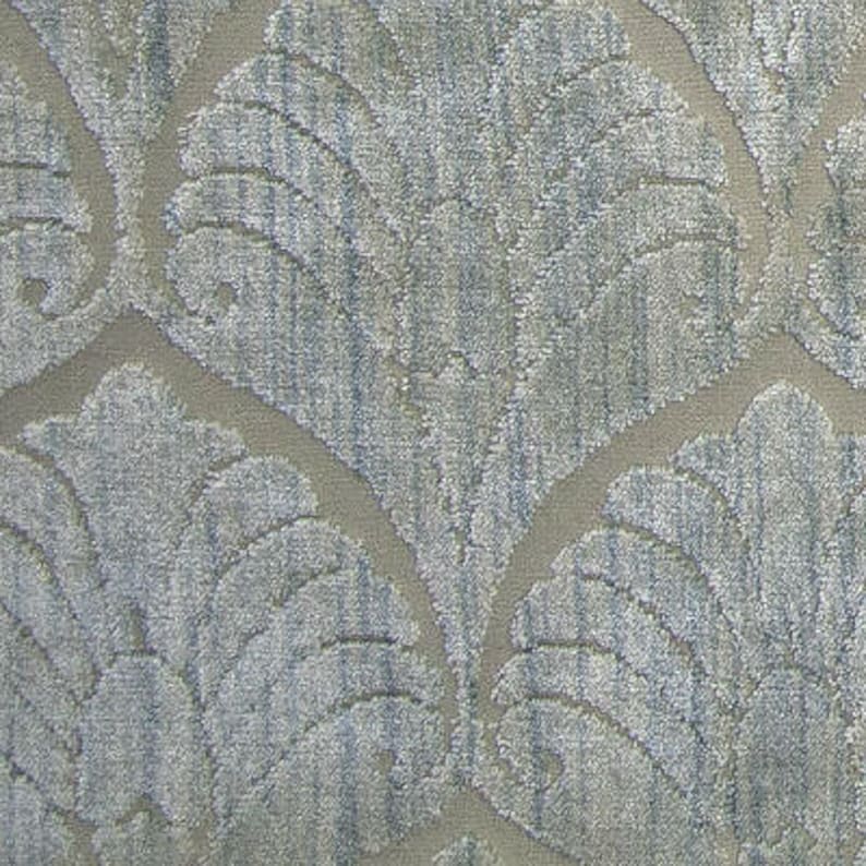 May include: A close-up of a textured fabric with a light gray background and a blue and white pattern of stylized leaves.
