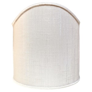 May include: A white fabric lampshade with a curved top and a textured surface.