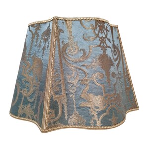 May include: A blue and gold patterned lampshade with a scalloped edge and gold trim.