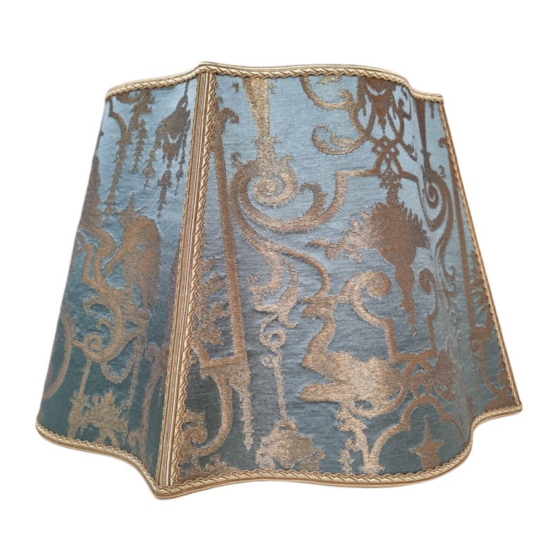 May include: A blue and gold patterned lampshade with a scalloped edge and gold trim.
