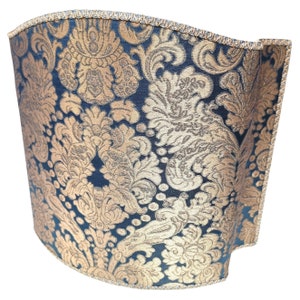 May include: A curved lampshade with a black background and a gold damask pattern.