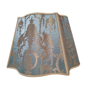 May include: A blue and gold lampshade with a decorative pattern. The lampshade has a scalloped edge and a gold trim.