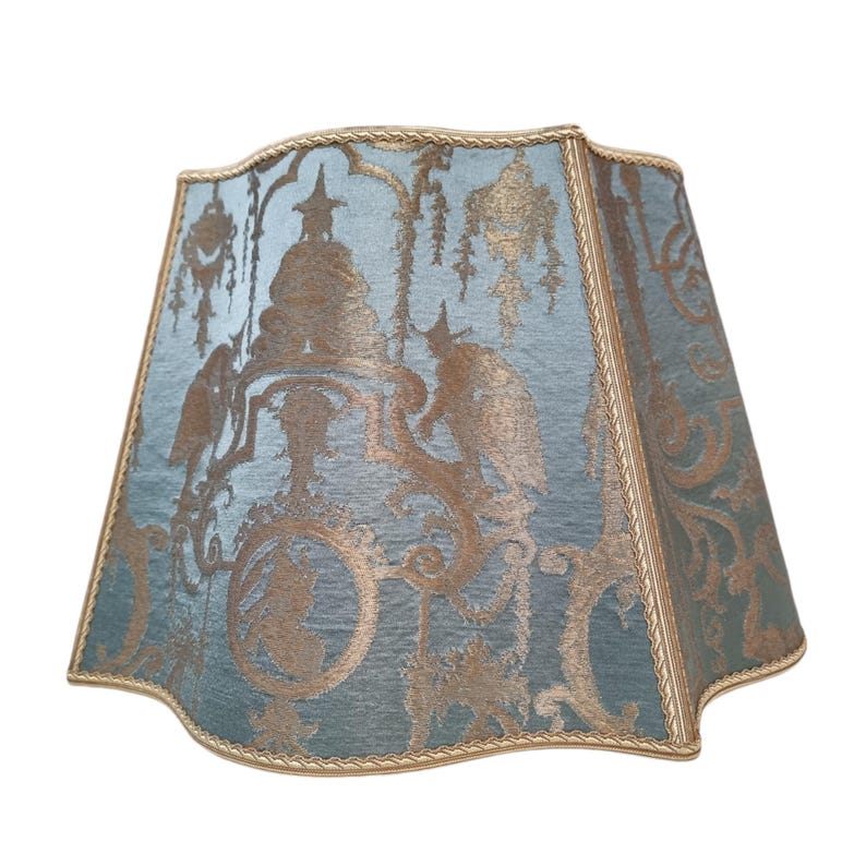 May include: A blue and gold lampshade with a decorative pattern. The lampshade has a scalloped edge and a gold trim.