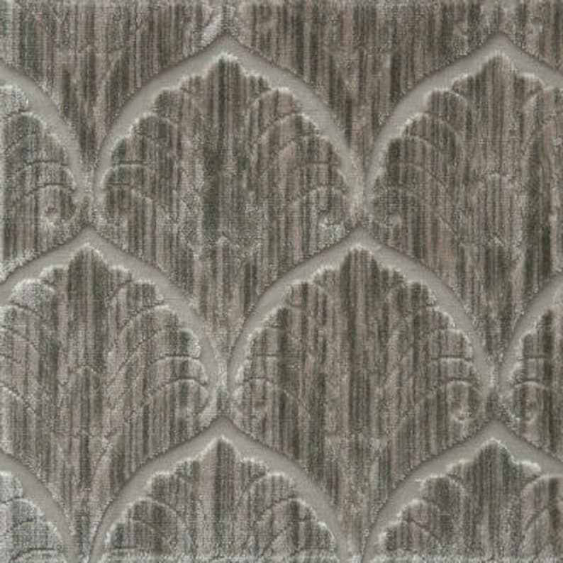 May include: A close-up of a textured fabric with a repeating pattern of stylized leaves in a light gray and brown color scheme.