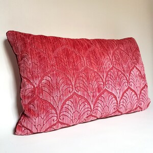 May include: A red velvet pillow with a white floral pattern. The pillow is rectangular and has a soft, plush texture.