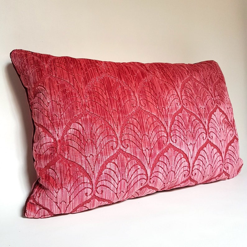 May include: A red velvet pillow with a white floral pattern. The pillow is rectangular and has a soft, plush texture.