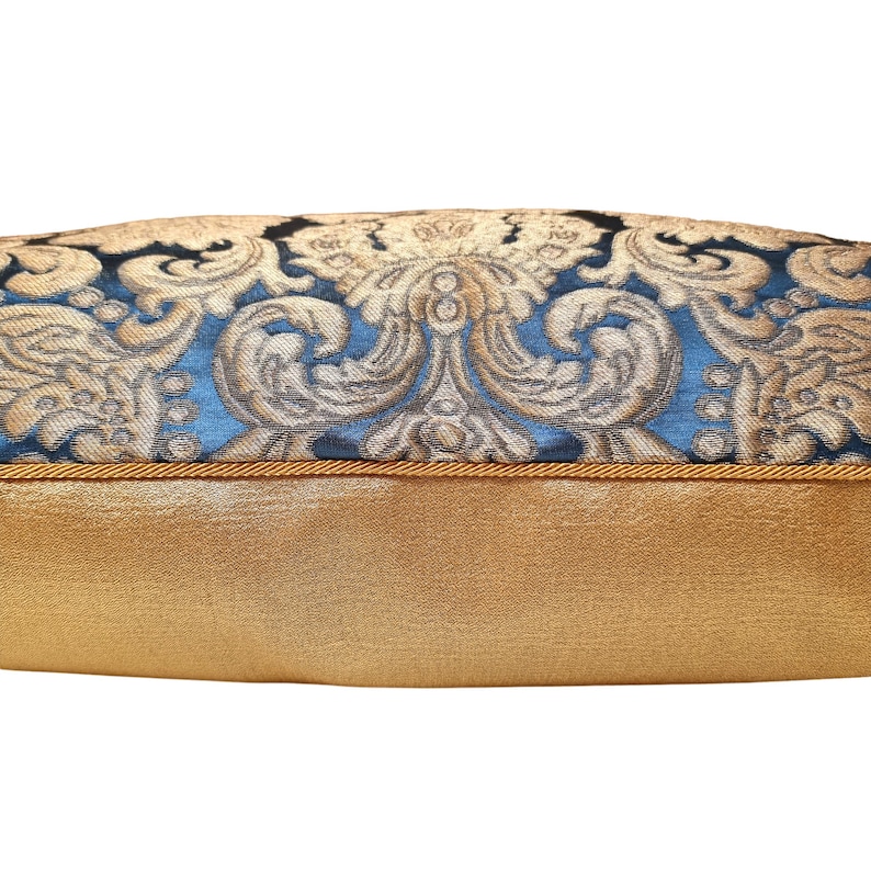 May include: A blue and gold patterned throw pillow with a gold trim. The pillow is made of a soft, luxurious fabric.