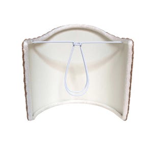 May include: A lampshade with a white interior and a brown textured border. The lampshade has a curved top and bottom, and a white metal frame for attaching to a lamp base. The shade is designed to diffuse light.