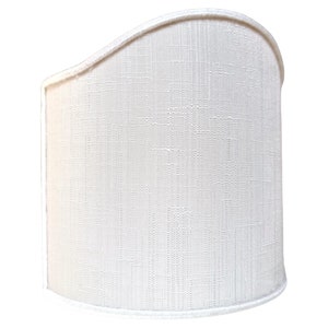 May include: A white fabric lampshade with a curved top and a textured surface.
