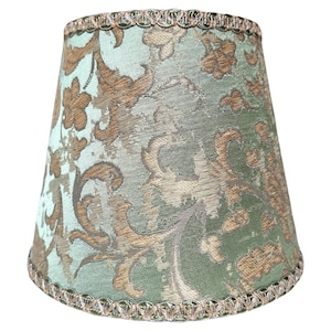 Pode incluir: Um abajur verde com um padr&atilde;o floral marrom e dourado e uma borda dourada.