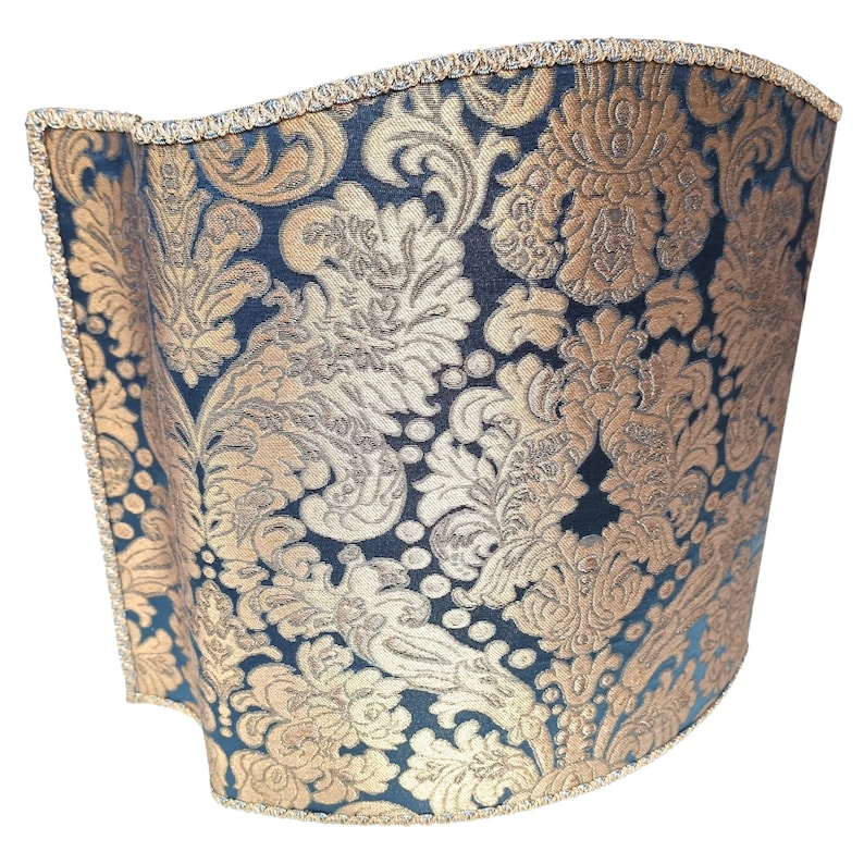May include: A black and gold lampshade with a damask pattern. The lampshade is curved and has a gold trim.