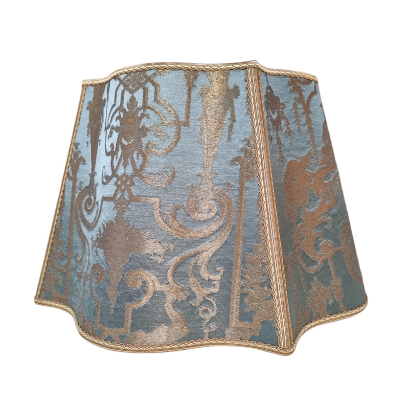 May include: A blue and gold lampshade with a decorative pattern. The lampshade has a scalloped edge and a gold trim.