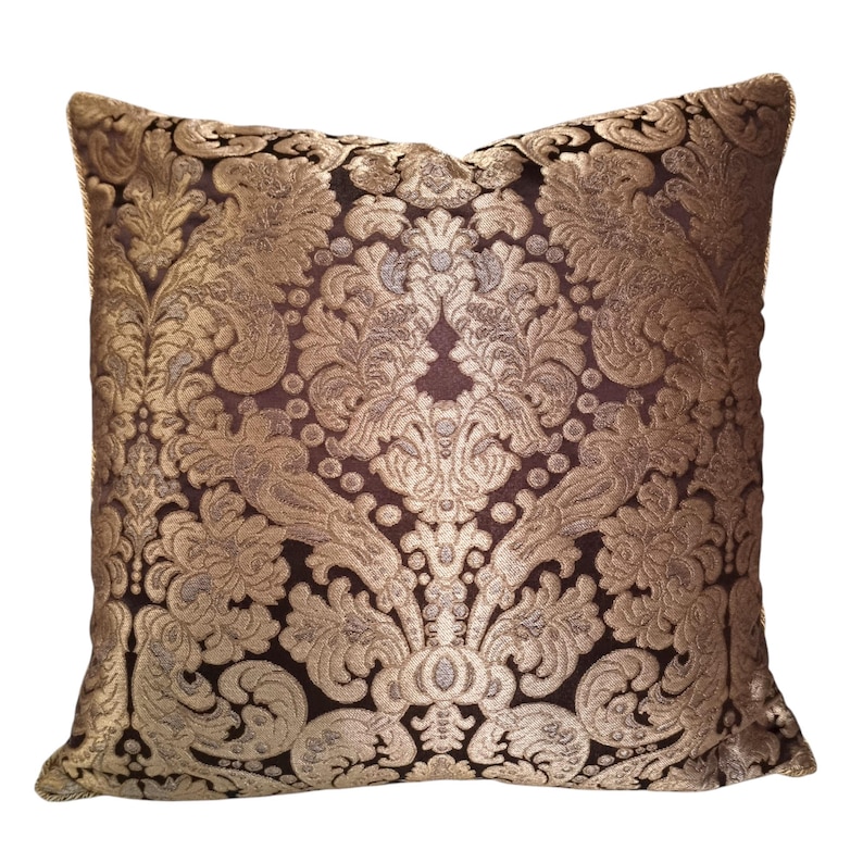May include: A square throw pillow with a brown velvet fabric and a gold damask pattern.