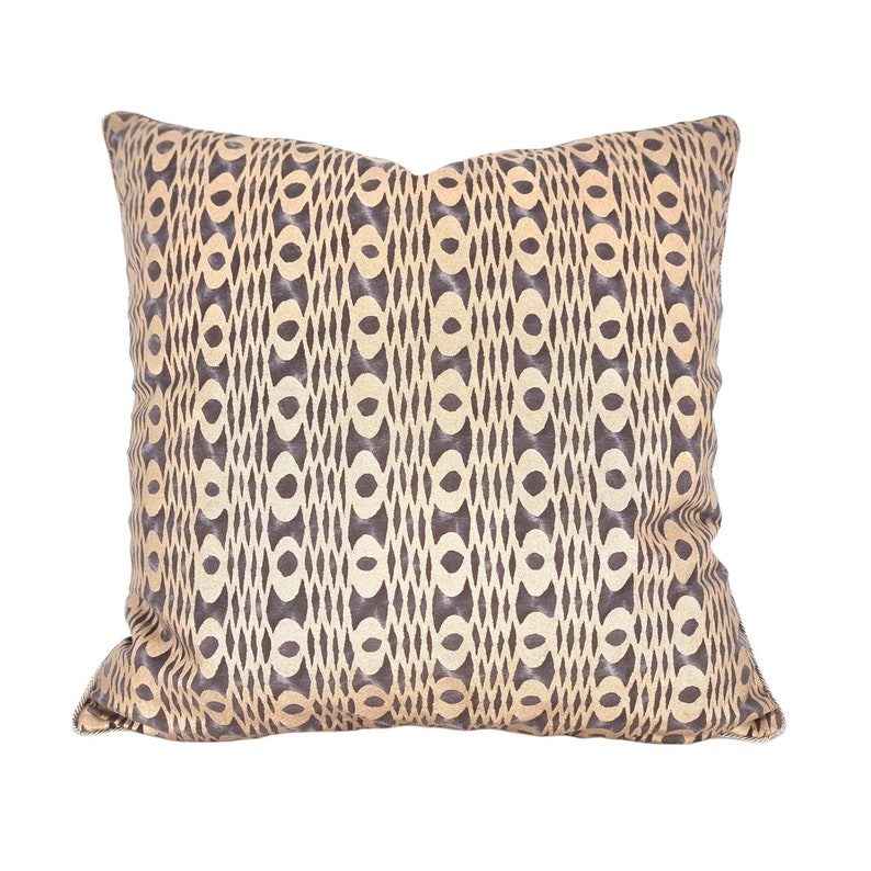 Op de afbeelding: Een decoratief kussen met een geometrisch patroon in beige en bruine tinten.