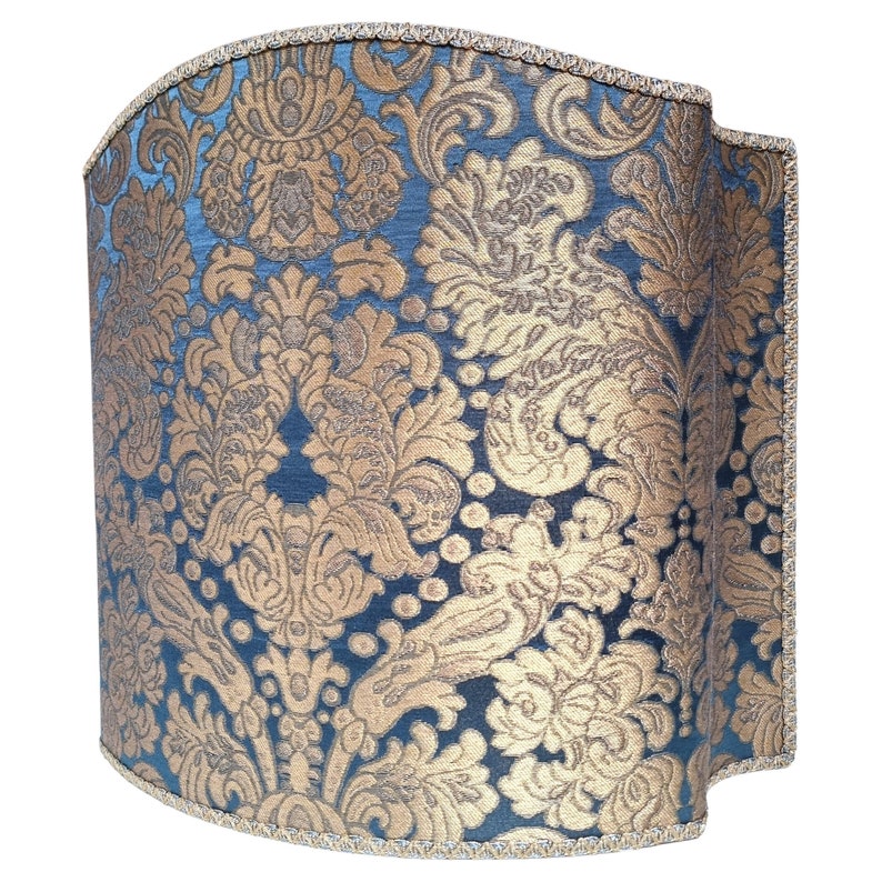 May include: A blue and gold patterned lampshade with a scalloped edge.
