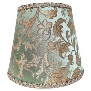 Pode incluir: Um abajur verde com um padr&atilde;o floral dourado e uma borda verde e dourada.