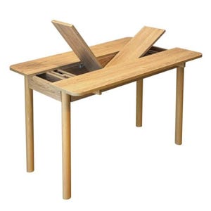 May include: A light oak wood table with four cylindrical legs and a rectangular top. The center section of the tabletop is partially open, revealing two hinged wooden panels that are angled upward, exposing the internal storage compartment.
