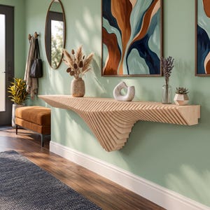 Puede incluir: Una mesa consola flotante de madera clara con un diseño geométrico texturizado, en capas y angular. La mesa está montada en una pared y presenta una superficie horizontal ancha con una estructura de soporte cónica y acanalada debajo.