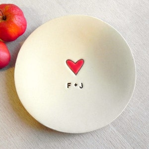 May include: White ceramic ring dish with a red heart and the initials "F + J" in black.