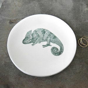 Puede incluir: Plato de cer&aacute;mica blanca para alhajas con un dise&ntilde;o de camale&oacute;n verde. El camale&oacute;n est&aacute; detallado con un patr&oacute;n floral.