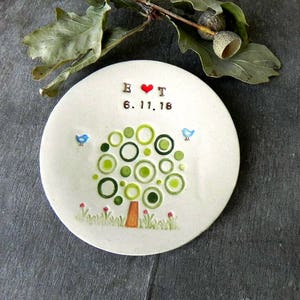 May include: A white ceramic ring dish with a green tree design, two blue birds, and the text "E &hearts; T 6.11.18".