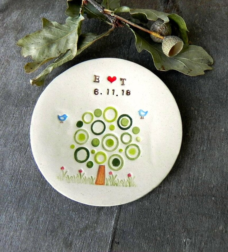 May include: A white ceramic ring dish with a green tree design, two blue birds, and the text "E &hearts; T 6.11.18".