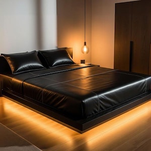 Könnte beinhalten: Ein niedriges Plattform-Bettgestell mit einer schwarzen lederartigen Oberfläche auf der Matratze und den Kissen. Das Bett wird von unten durch warmes, sanftes Licht beleuchtet, was einen leuchtenden Effekt auf dem hellen Holzboden erzeugt.