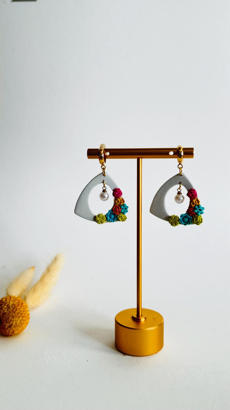 Colorful hand-sculpted flower earrings on a white triangle hoop with pearl drop