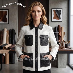 Puede incluir: Una chaqueta blanca con textura de cocodrilo, con cuello, tapeta frontal y cuatro bolsillos de parche en textura de avestruz negra. La prenda incluye botones plateados y el texto LegacycraftedStore es visible en la imagen.