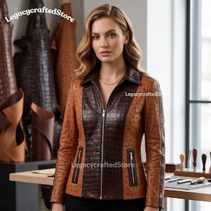 Peut inclure: Une veste à manches longues avec un corps en cuir texturé autruche beige et un panneau central, un col et des bandes latérales en cuir texturé crocodile marron foncé. La veste présente une fermeture éclair dorée et deux poches zippées.