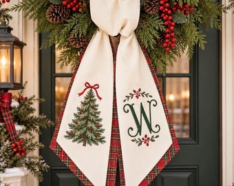 May include: A cream-colored fabric door hanger featuring a red and green plaid border. The left panel displays an embroidered Christmas tree with a red bow, while the right panel features an embroidered green letter W with red berries.
