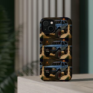 May include: A smartphone case featuring a repeating pattern of a light blue off-road SUV with large black tyres and red rims. The vehicle is depicted in a night setting with a dark background and a single orange light source visible above the truck.