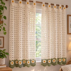 May include: A pair of off-white crochet curtains featuring a grid pattern, hanging from a wooden rod. The top and bottom edges are decorated with a row of crocheted daisy motifs with yellow centers and white petals on a green base.