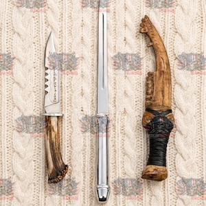 May include: A set of three items including a small knife with a serrated blade and antler handle, a long slender silver-toned metal letter opener, and a curved decorative object with a textured bone-like handle wrapped in black cord.