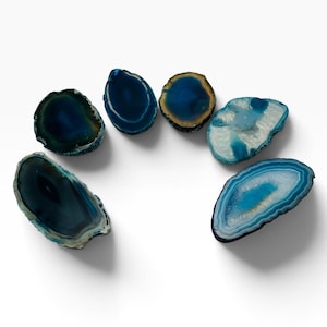 May include: Six polished agate slices arranged in a semi-circle. The stones feature various shades of blue, ranging from deep navy to light turquoise and white, with natural concentric banding patterns and irregular, organic, rounded edges.
